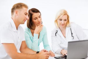 healthcare, medical and technology concept - doctor with patients looking at laptop